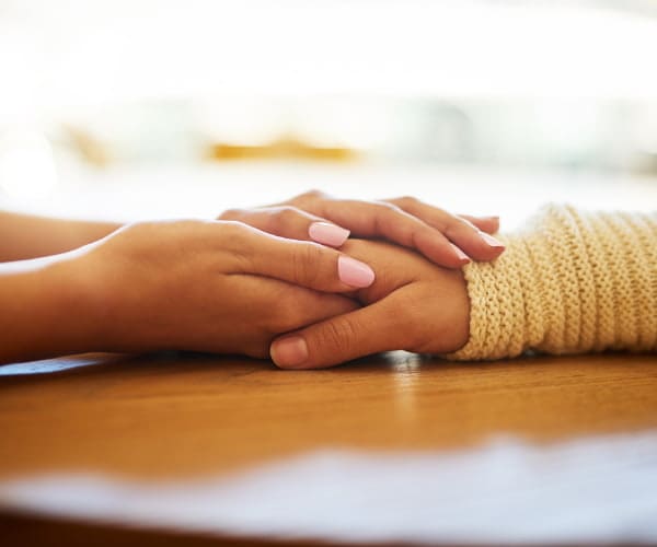 Two people hold hands offering each other support in their time in need