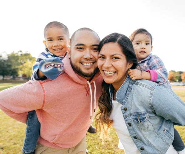 A mom and dad play outside with their two sons having a fun time